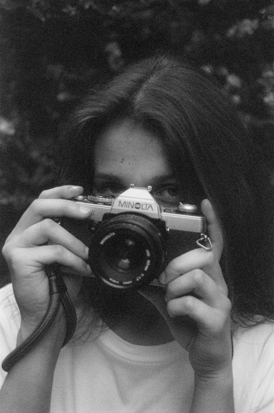 Person holds a vintage film camera up to their face.