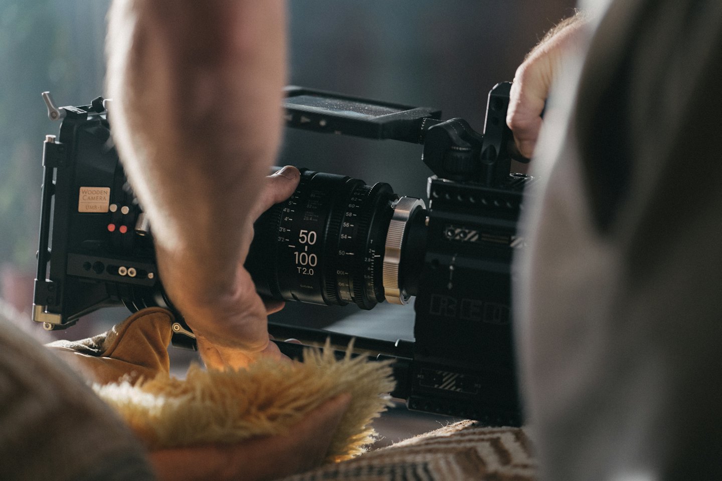 Hands adjusting a professional video camera lens.