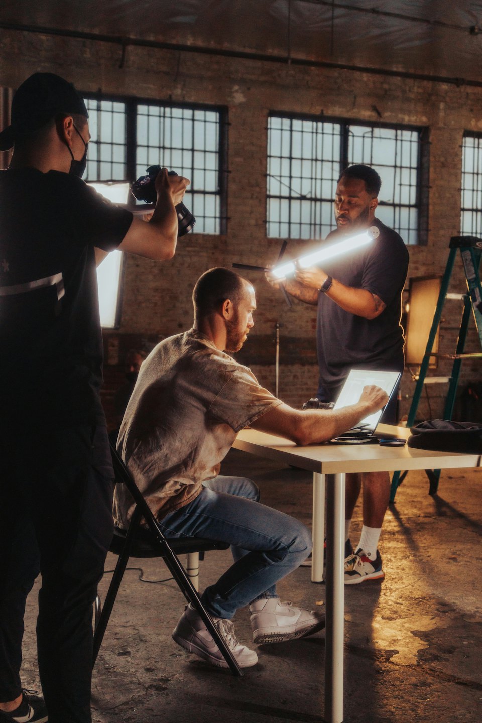 Three men collaborate on a creative project in an industrial studio.