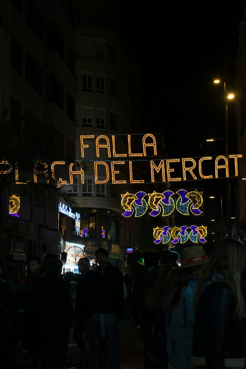 Crowd gathered under glowing festival lights on a city street.