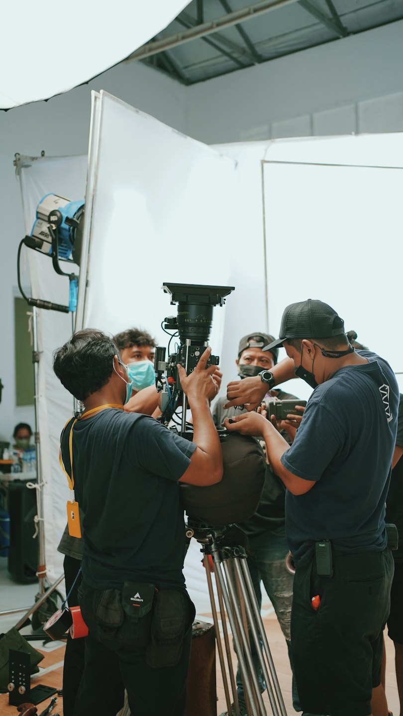 Men collaborating around a professional film camera in a studio.