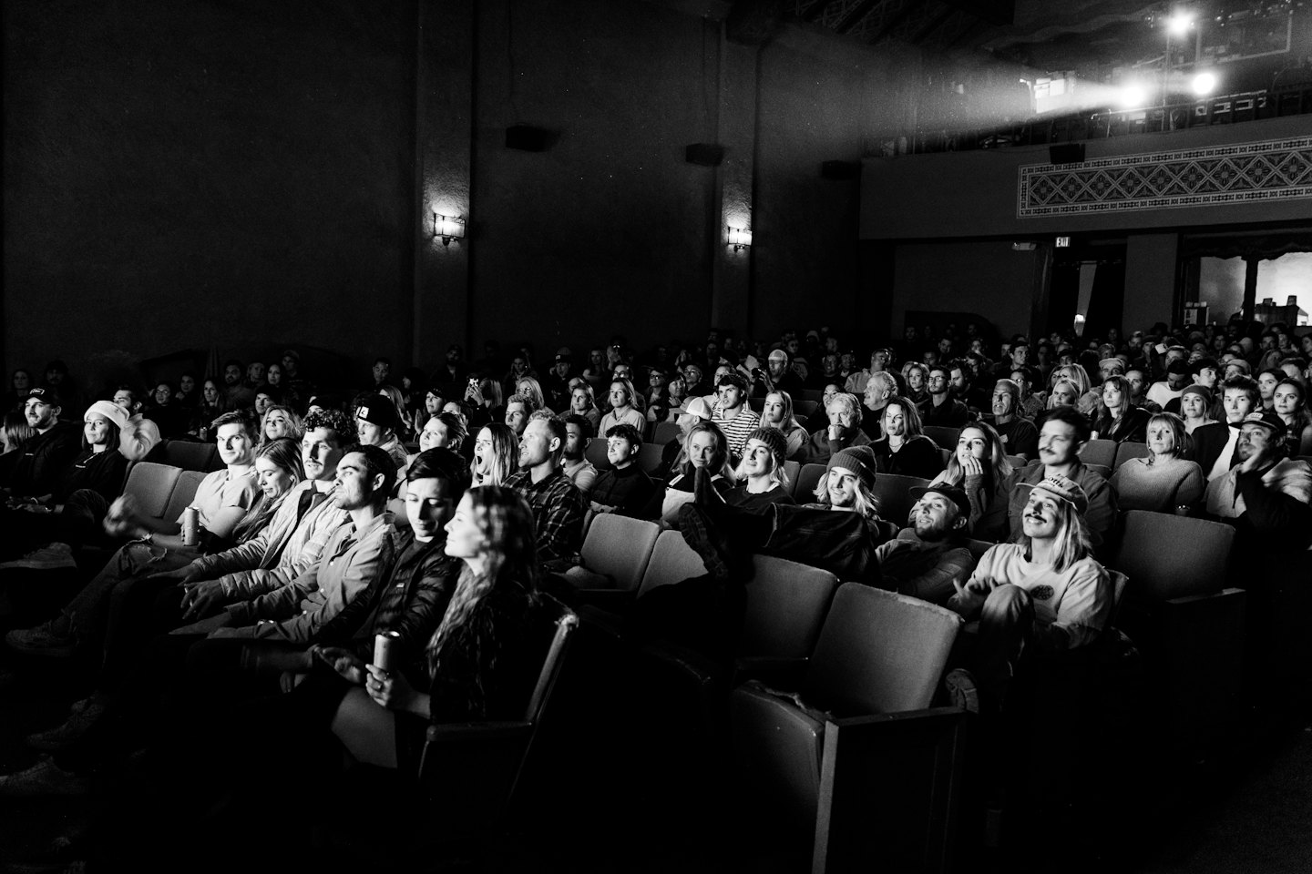 Audience watches a performance in a dark theater auditorium.