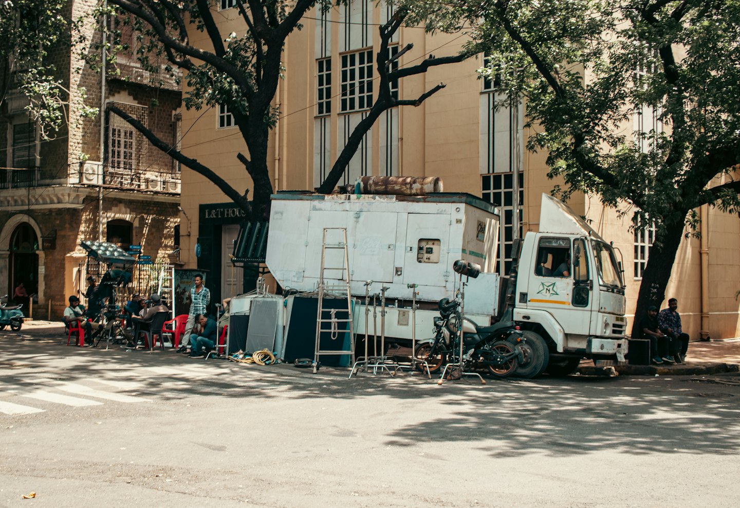 Film crew members working near a production truck on city street.
